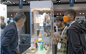 Exhibitors and attendees having a conversation with a product showcase in the background